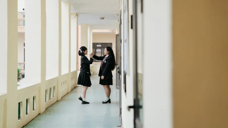 교복을 입은 두 학생이 복도에서 마주 보고 서 있는 모습